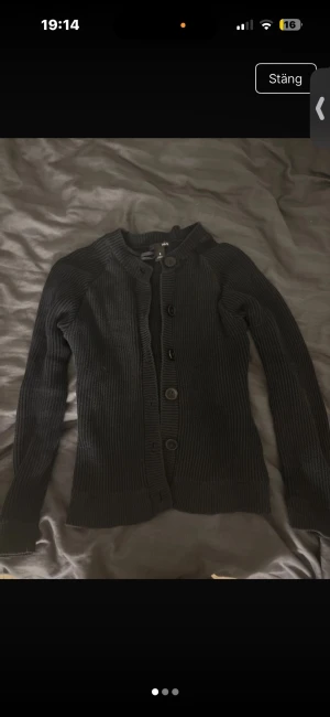 Svart ribbad kofta från H&M - Klassisk svart ribbad kofta från H&M med långa ärmar och knäppning framtill. Koftan har en rundad halsringning och breda muddar vid ärmslut och nederkant. Perfekt att slänga över en t-shirt eller linne för en enkel och stilren look. Pris kan diskuteras!!