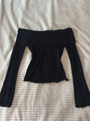 Svart off shoulder topp Gina Tricot - Trendig svart off shoulder topp från Gina Tricot med långa ärmar och figurnära passform. Mjuk och stretchig känsla. Inget fel med den