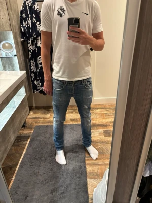 Blå slitna skinny jeans herr - Säljer ett par blå skinny jeans med slitningar och hål på knäna. Jeansen har en tvättad look, låg midja och smal passform. Klassiska fem fickor och dragkedja. Perfekta för en avslappnad och trendig stil. 7/10 skick, Jeansen är väldigt eftertraktadade och finns inte längre på marknad. W och L på bild 6, enda defekten på bild 7