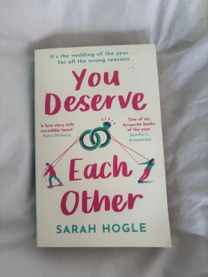You Deserve Each Other av Sarah Hogle - En romantisk och humoristisk roman på engelska med färgstarkt omslag i vitt, rosa och turkos. Boken handlar om Naomi och Nicholas och deras komplicerade relation inför ett bröllop. Perfekt för dig som gillar feelgood och romantik med mycket humor.