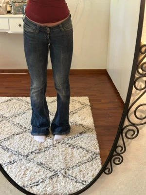 Blå bootcut jeans med låg midja - Lågmidjade bootcut jeans från Cheap Monday. Minimal slitning längst ner på ena byxbenet men bra skick i övrigt. Säljer pga att de är för långa.