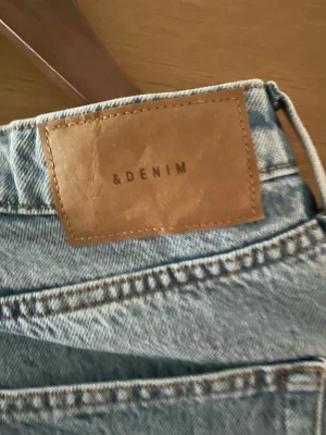 Ljusblå vida jeans från &Denim - Säljer ett par ljusblå jeans från &Denim med rak passform och råa, avklippta benslut. Klassisk femficksmodell i mjuk denim som ger en avslappnad vibe. Perfekta till sneakers eller boots för en chill look. Hög midja