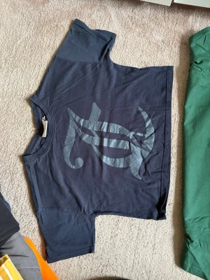 Svart Juicy Couture t-shirt - Juicy Couture t-shirt i svart med stort tryck framtill. Klassisk rund hals och korta ärmar. Tillverkad i mjuk bomull som känns skön mot huden. Perfekt för dig som gillar streetwear och vill ha en enkel men snygg look.