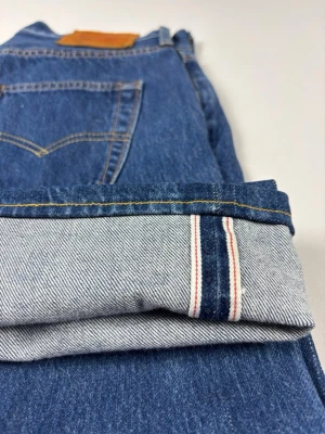 Levi's 501 Original Fit Selvedge Herrjeans Klassisk Blå Selvedge Denim (W30 L32) - Levi’s 501 Selvedge Jeans Riktigt snygga & klassiska Levi's 501 med selvedge!  Färg: Blå Straight leg Storlek: W30 L32 Skick: A-B-Grade, Mycket bra skick Mått [platt] (±1 cm): A: 36 cm B: 97 cm C: 27 cm D: 19,5 cm Passar inte på modellen som är 189 cm lång, han har fått dra ner jeansen rejält endast i syfte att visa passformen. Tveka inte att höra av dig vid frågor eller funderingar.  Skickas snabbt!