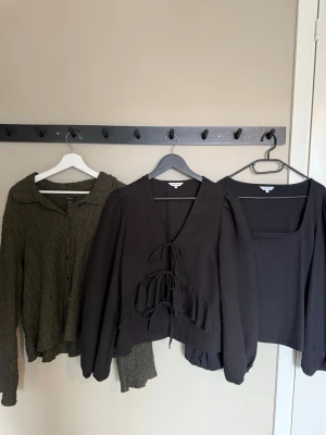 Svarta och gröna toppar i olika stilar - Säljer ett paket med flera toppar i svart och mörkgrönt. Blandade modeller med lång ärm, omlott, snörning och spetsdetaljer. Några har v-ringning och croppad passform. Perfekt för dig som gillar stilrena och trendiga plagg.