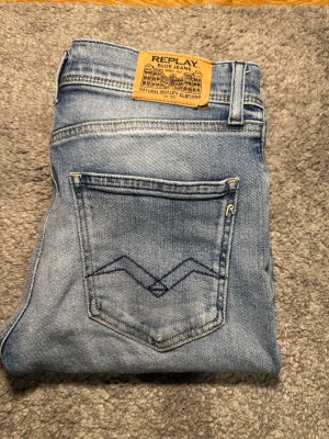 Ljusblå Replay jeans wallys - Snygga ljusblå jeans från Replay med klassisk femficksmodell och raka ben. Jeansen har en läderpatch med Replay-logga bak i midjan och diskret broderad detalj på bakfickan. Tillverkade i mjuk denim med lätt tvättad look. Dem har ett jätte litet hål som inte syns på man ser de på bild nr 4