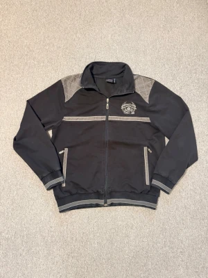 Svart sportjacka med grå detaljer - Säljer en svart hoodie med dragkedja och grå detaljer på axlar, ärmslut och fickor. Hör av dig vid frågor och behöva av fler bilder!☺️☺️