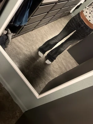 Svarta bootcut jeans med patch - Säljer ett par svarta bootcut jeans med cool patch på bakfickan. Jeansen har låg midja och klassisk femficksdesign. Perfekta för dig som gillar en avslappnad men trendig look.❤️