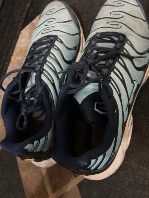 Blå sneakers med svarta detaljer - Säljer ett par sneakers i ljusblått med svarta och vita detaljer. Skorna har snörning och en synlig luftbubbla i sulan. Ovandelen är i syntetmaterial och mesh för bra andningsförmåga. Perfekta för dig som gillar sportig stil.