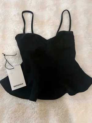 Svart korsett-topp från Bershka - Helt ny svart korsett-topp från Bershka med figurnära passform och tunna axelband. Köpt på BERSHKA i Spanien 🍸🍸🍸