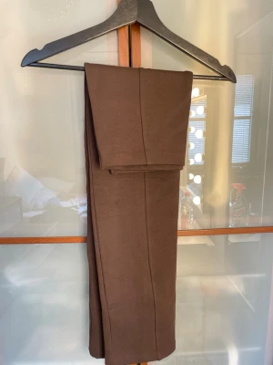 Brun långkjol från Gina Tricot - Säljer en stilren brun långkjol från Gina Tricot. Kjolen har en rak passform och är tillverkad i ett mjukt material som känns bekvämt mot huden. Perfekt att matcha med en enkel topp eller stickad tröja för en trendig look.
