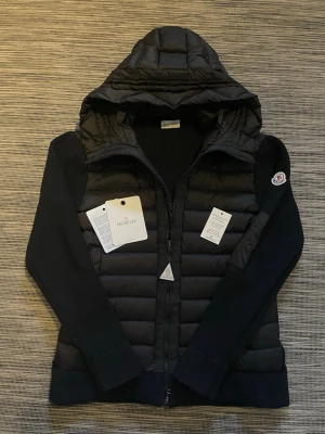 Svart Moncler cardigan - Säljer en riktigt snygg cardigan från moncler! Cardiganen är i mycket bra skick och har inga defekter. Nfc-scan och Qr-kod funkar som dem ska. Perfekt  till vinter/vår väder! Om ni har några frågor så är de bara att höra av er😊