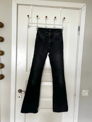 Svarta bootcut jeans från ONLY XS - Säljer ett par svarta bootcut jeans från ONLY i storlek XS/32. Jeansen har hög midja, klassisk femficksdesign, med vanliga fickor där bak och  utsvängda ben. Materialet är mjukt denim med lite stretch för extra komfort. Perfekta för en trendig och avslappnad look.