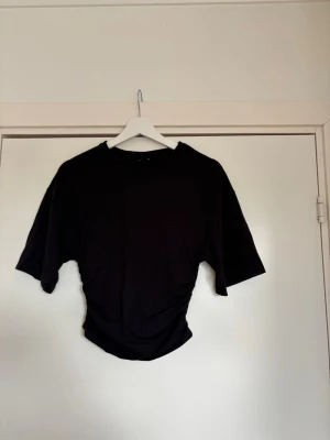 Svart topp - En fin svart croppad topp med korta stora ärmar och rynkade detaljer i midjan från Gina Tricot. Använd 1 gång.