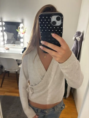V-ringad stickad kofta❤️ - Säljer en beige stickad omlottopp med långa ärmar och knyt i sidan. Tröjan har en djup v-ringning och är croppad i modellen. Jätte jätte mjukt material.💞💞original pris: 299💞