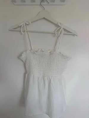 Vit linnetopp med knytband - Söt vit linnetopp med axelband som knyts upptill. Från H&M och sällan använt, säljer på vinted också nadiaogen💞