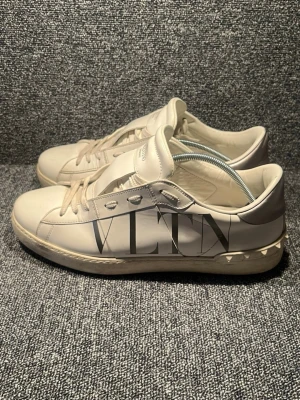 Vita Valentino VLTN sneakers - Snygga vita sneakers från Valentino med VLTN-logga på sidan KVITTO FINNS. Skorna är låga och har klassisk snörning samt detaljer i vitt läder. Perfekta för dig som vill ha en clean och exklusiv look med en touch av lyx. Frågor eller fundering bara att skriva