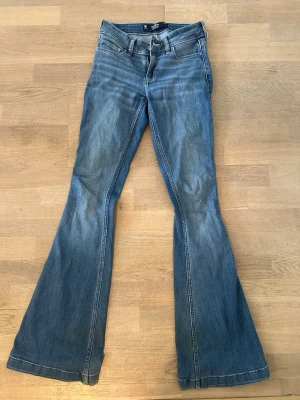 Blå utsvängda jeans från Hollister - Säljer ett par blå jeans från Hollister med låg midja och utsvängda ben. 