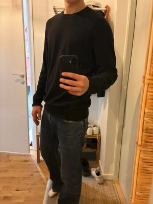 Svart basic sweatshirt - En enkel svart sweatshirt med rund hals och långa ärmar. Tröjan har en avslappnad passform och ribbade muddar vid ärmslut och nederkant. Perfekt att matcha med jeans eller andra byxor för en clean look.