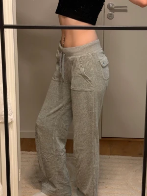 Gråa mjukis - Juicy Couture - Gråa ikoniska Juicy Couture mjukisbyxa med raka ben och loose fit. Dessa är def en stor favorit och varit länge! Säljer pga använder de andra färgerna jag har mer nowdays,                                                                       ⭐️Säljes i använt skick, tagits väl omhand om              ⭐️Byxorna är rena, hela och utan fläckar                              💭Har du frågor? Skriv på annonsen och jag svarar så fort jag kan!