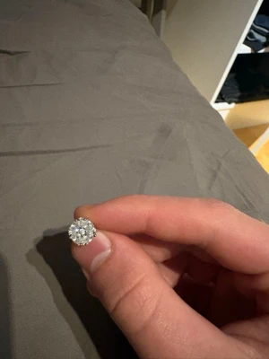 Glittrande örhänge med stenar - Säljer ett snyggt örhänge i silverfärg med en stor rund glittrande sten i mitten, omgiven av mindre stenar som ger extra bling. Perfekt för dig som gillar att sticka ut med dina accessoarer.