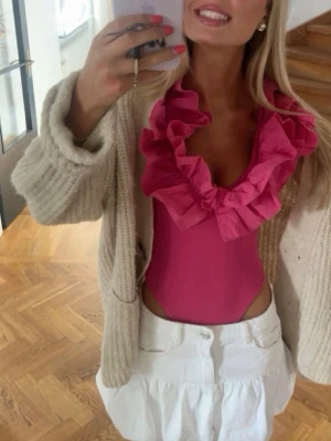 Viral Zara body - Snygg rosa bodysuit med stora volanger runt urringningen. Modellen är ärmlös och har en djup v-ringning framtill. Perfekt för dig som vill sticka ut med en färgstark och trendig topp. Størrelse L. Kan sende dersom kjøper betaler frakt