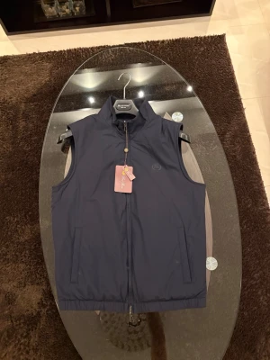Reversible Loro Piana väst - Snygg mörkblå väst med hög krage och hel dragkedja framtill. Västen har två sidofickor och en minimalistisk design utan synliga mönster. Perfekt för lager-på-lager och enkel att matcha med olika outfits.