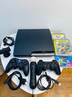 PlayStation 3 Slim med tillbehör - Säljer en svart PlayStation 3 Slim med två trådlösa handkontroller, PlayStation Move-kontroll, kamera och flera spel. Konsolen har en stilren, matt finish och klassisk design. Perfekt för gamingkvällar med vänner eller familj.