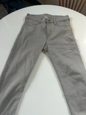 Hm jeans  - Snygga grå jeans med rak passform och klassisk femficksdesign. Jeansen har bälteshällor, knappgylf och är tillverkade i ett mjukt denimtyg. Perfekta för en clean och stilren look.