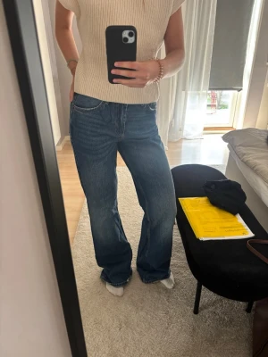 Blå raka jeans med hög midja - Säljer ett par klassiska blå jeans med rak passform och hög midja. Jeansen har fem fickor, knappgylf och är tillverkade i ett slitstarkt denimtyg. Super snygga och i bra skick!!