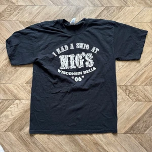 Svart Gildan t-shirt med tryck - Svart t-shirt från Gildan med vitt tryck på bröstet där det står 'I had a swig at Nig's Wisconsin Dells 06'. Klassisk passform och rund hals. Tillverkad i bomull för en skön känsla.