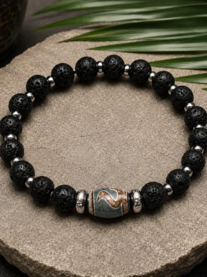Svart pärlarmband med en ädelsten. - Armband med svarta lava pärlor, silvriga mellandelar i rostfritt stål. Centerpärlan är en ädelsten , Tibetan dzi agat. Armbandet är ca 20 cm, elastiskt. Endast detta exemplaret.
