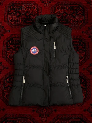 Canada goose väst - Snygg Canada goose väst perfekt för våren, sommaren och hösten. Passformen är för nån som har M-S även om det står L inuti den. | Längd 64 cm | Bredd 50 cm | pris går att diskutera vid snabbaffär / bundle köp! 💯 men kjedjan är sönder men de går att använda knapparna