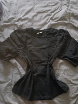 Svart topp med broderade detaljer - Säljer en svart topp med korta ärmar och fina broderade detaljer. Toppen har rund halsringning och är tillverkad i bomull, vilket gör den både bekväm och snygg. Perfekt för dig som gillar stilrena plagg med det lilla extra.