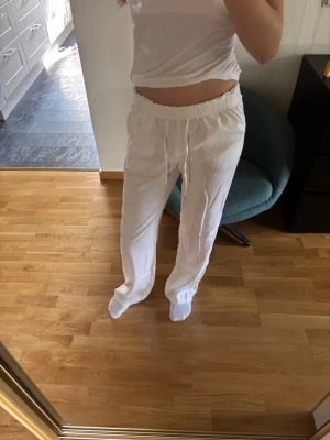 Vita linnebyxor med bakfickor - Säljer ett par vita linnebyxor med avslappnad passform med snöre i midjan. Byxorna har raka ben och sidofickor, perfekta för en chill och stilren look. Materialet är luftigt linne som passar bra till sommaren. Säljer pga att de aldrig har kommit till användning. Byxorna är helt oanvända. Storleken är xs-tall, alltså extra långa i benen, skriv om ni vill ha mått!