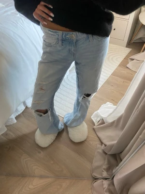 Ljusblå ripped baggy/lose bootcut jeans💓 - Säljer ett par ljusblå jeans med baggy/lose bootcut  ben och flera slitningar och hål på både lår och knän. Jeansen har fem fickor och är ifrån Gina tricot 14+ i storlek XS💞