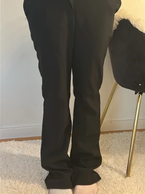 Svarta raka kostymbyxor - Säljer ett par svarta kostymbyxor med rak passform och hög midja. Byxorna har diskreta fickor och klassisk look, perfekta till en snygg outfit. Materialet ser ut att vara mjukt och följsamt, vilket ger en clean och stilren vibe.