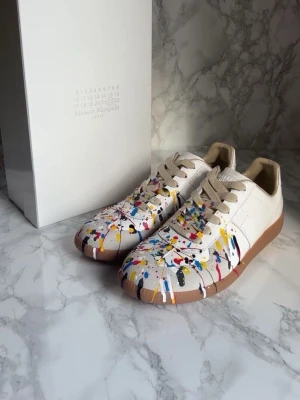 Maison Margiela sneakers med färgstänk - Vita maison margiela skor aldrig använda med splatter på. Inga defekter o h dem är redo att gå pris kan diskuteras 