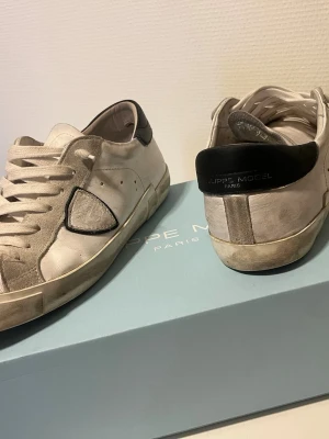Vita Philippe Model sneakers med svart detalj - Skorna är köpta från merchsweden priset går att diskutera .