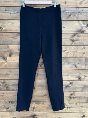 Prada Svarta leggings med dragkedja - Säljer ett par svarta leggings från Prada med smal passform och dragkedjor vid bensluten. De har en enkel, stilren design utan synliga fickor eller detaljer. Perfekta att matcha med oversized tröjor eller hoodies för en clean look.0137