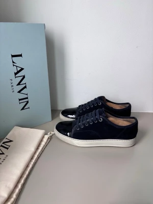 Lanvins  - Säljer ett par snygga lanvins i mörkblå färg. Storlek UK7 (EU41), cond 8,5/10 liten bit av sulan har chippats av samt heeldrag men mockan i fint skick! Medkommer OG box och dustbag!