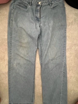Ljusblå raka jeans - Säljer ett par ljusblå jeans med rak passform och klassisk femficksdesign. Jeansen har hög midja och är tillverkade i denim med en lätt tvättad look. Perfekta för en avslappnad stil och passar till det mesta i garderoben.
