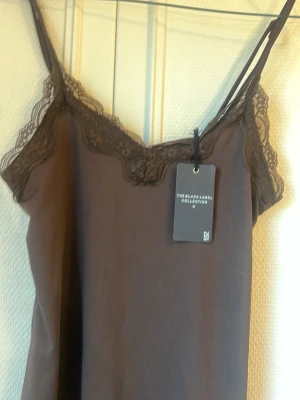 Brown Lace linne  - Det här är ett linne med spets både nedtill och upptill. Den är v-ringad. Den har en jättefin brun färg med snygga spets detaljer. Säljer på grund av att den inte var min smak. Den har en mörkare prick som tillkom med linnet. Ingen större utan går säkert bort. Den syns knappt på bilden. 