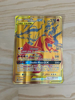 Pokémonkort Reshiram & Charizard GX - Säljer ett samlarkort från Pokémon TCG med Reshiram & Charizard GX i TAG TEAM-version. Kortet har en guldfärgad, glansig yta med detaljer i rött och blått. Perfekt för dig som gillar att samla eller spela Pokémonkort.