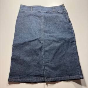 Sisley Blå jeanskjol med hög midja - Klassisk blå jeanskjol i rak modell med hög midja och bälteshällor. 0397