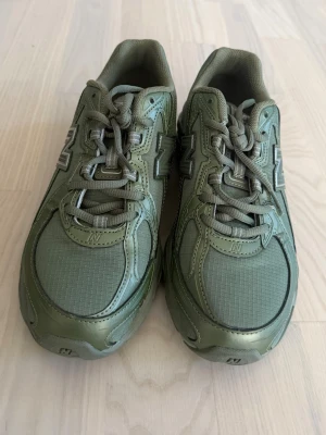 Olivgröna New Balance 740 sneakers - Säljer ett par olivgröna New Balance 740 sneakers med mesh och syntetdetaljer. Skorna har klassisk N-logga på sidan, snörning och robust sula med ABZORB-dämpning. Perfekta för dig som gillar streetwear och sportig stil.