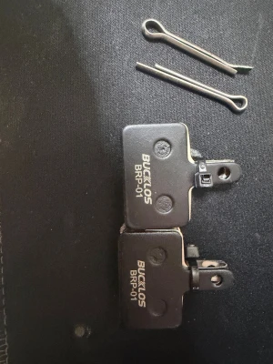 Bucklos BRP-01 bromsbelägg cykel - Säljer ett par svarta Bucklos BRP-01 bromsbelägg för cykel. Tillverkade i metall med slitstark yta och inkluderar två metallclips för montering. Perfekt för dig som behöver nya bromsbelägg till din cykel.