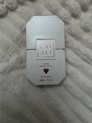 Kayali Utopia Vanilla Coco 21 parfym - Kayali Utopia Vanilla Coco 21 Eau de Parfum i en elegant, multifacetterad glasflaska med guldigt lock. Doften har en lyxig vit och roséguldig förpackning och rymmer 50 ml. Perfekt för dig som gillar söta, tropiska och vaniljiga dofter.