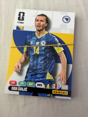 Panini fotbollskort Ivan Šunjić - Säljer ett Panini fotbollskort med  Bosnien och Hercegovinas landslag. Kortet har färgerna blå, gul och vit med spelarens namn, . Perfekt för samlare av fotbollskort.