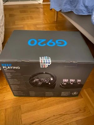 Logitech G920 ratt och pedaler - Säljer ett Logitech G920 racing ratt och pedalset. Ratten har svart och silver detaljer, och pedalerna är i metall med svart bas. Perfekt för racing på konsol eller PC. Ergonomisk design och realistisk känsla för gaming.